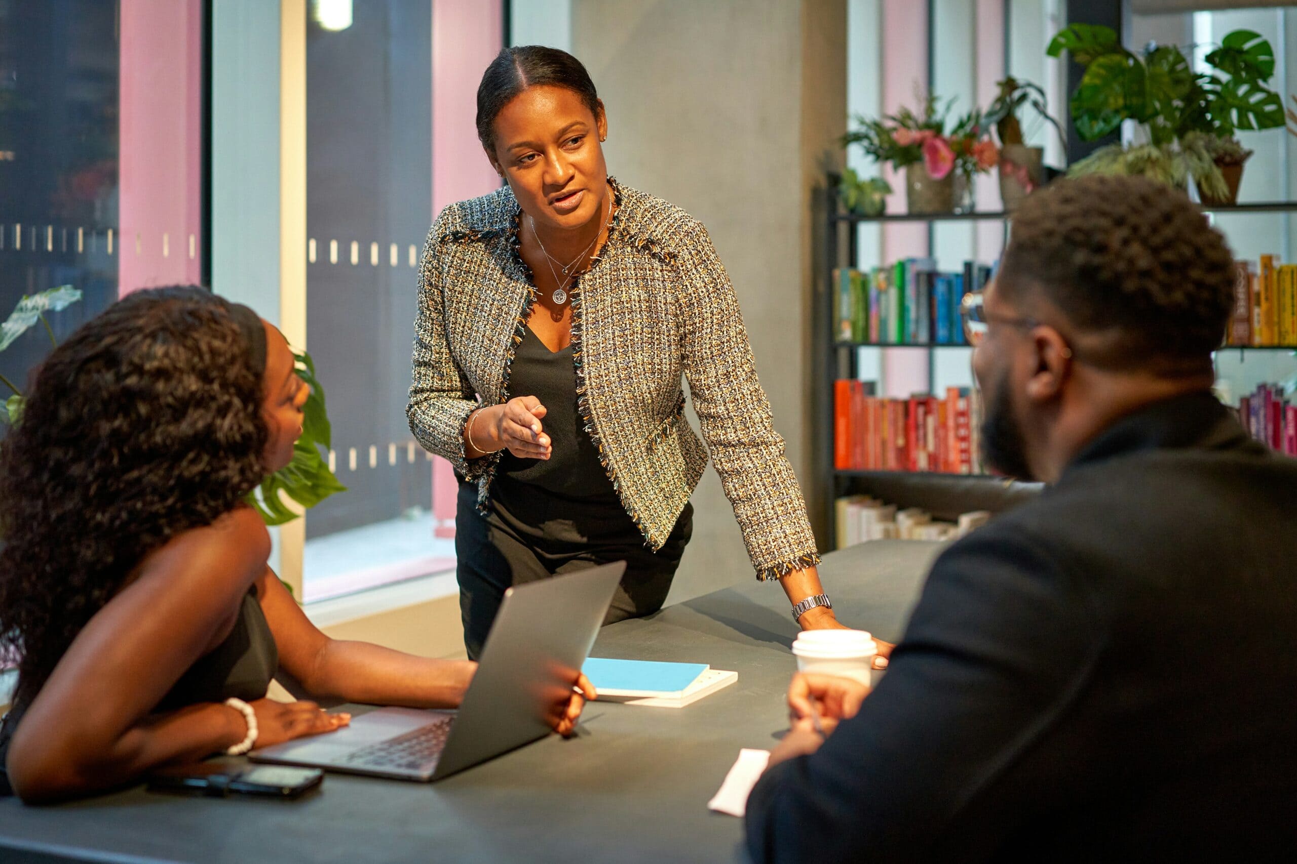 A professional woman leading a meeting concerning what makes a good IT consultant with two colleagues in an office environment at night.